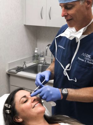Woman smiling while getting BOTOX injections between her eyebrows
