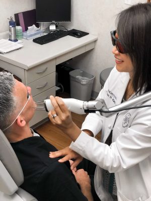 Dr. Karen Kim treating a male patient's melasma with a laser device