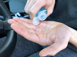 Man washing his hands with hand sanitizer in his car