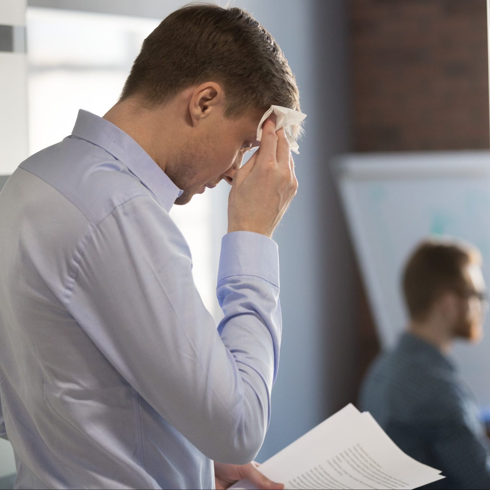 Man drying excessive sweat on his forehead