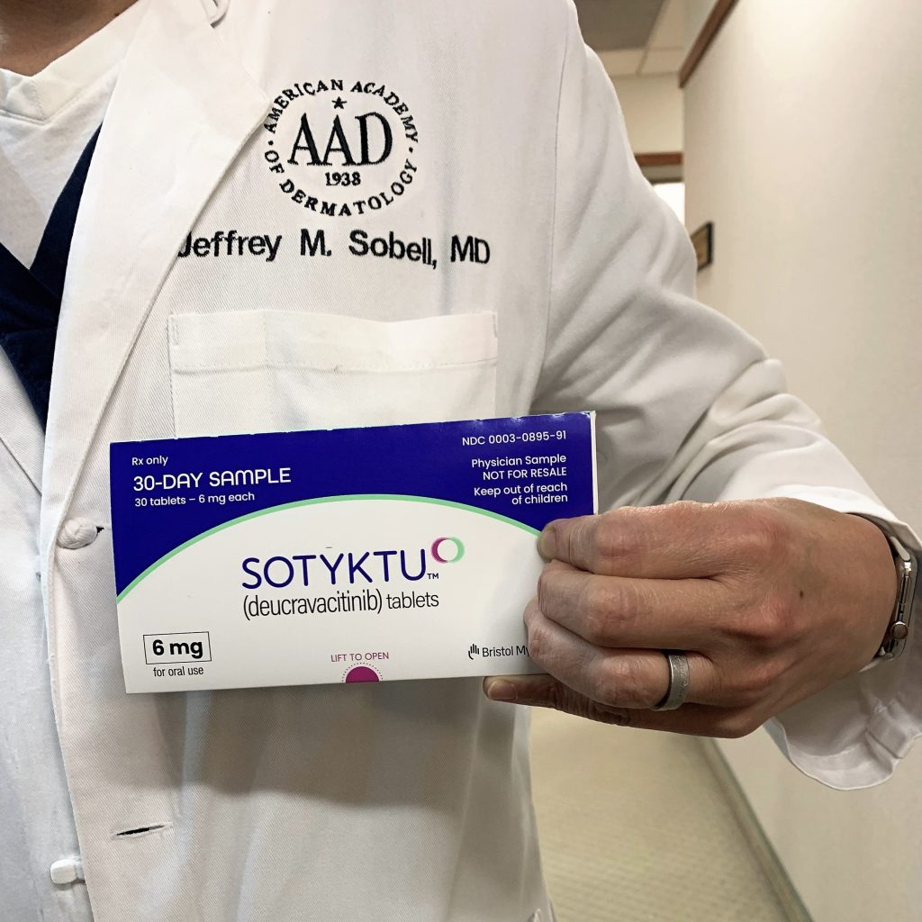 Dr. Sobell holding a box of the breakthrough pill treatment for psoriasis, Sotyktu