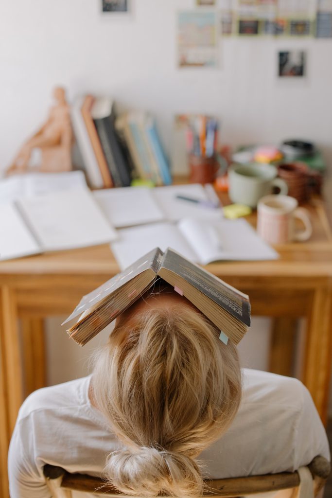 Stressed student hiding her face under a book