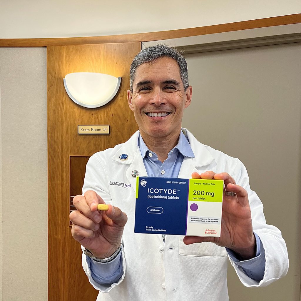 Dr Sobell holding the-new ICOTYDE pill in one hand and the box in the other.